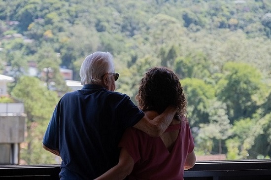 Cid Moreira e a esposa, Fátima, olham a vista de sua janela em seu apartamento em Petrópolis. Eles se abraçam.