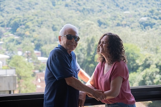 Cid Moreira e a esposa, Fárima, se olham enquanto estão apoiados na janela do apartamento em Petrópolis.