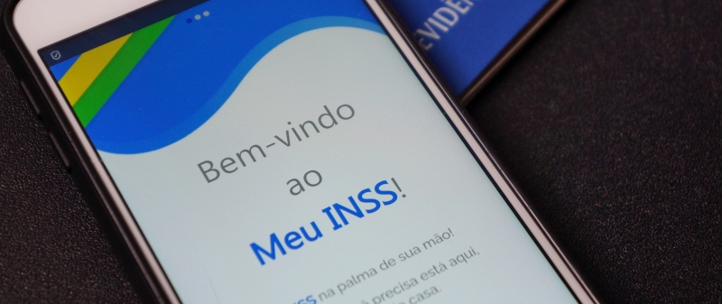 Um celular com a tela inicial do aplicativo Meu INSS. Imagem ilustra a notícia sobre a Operação Pente-Fino do INSS.