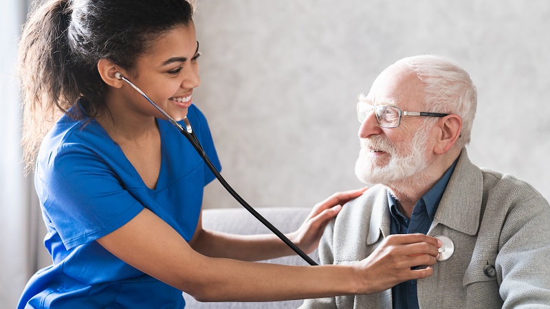 Mulher (enfermeira ou médica) examina o coração de um homem idoso. A imagem ilustra o artigo sobre efeitos do envelhecimento no coração.
