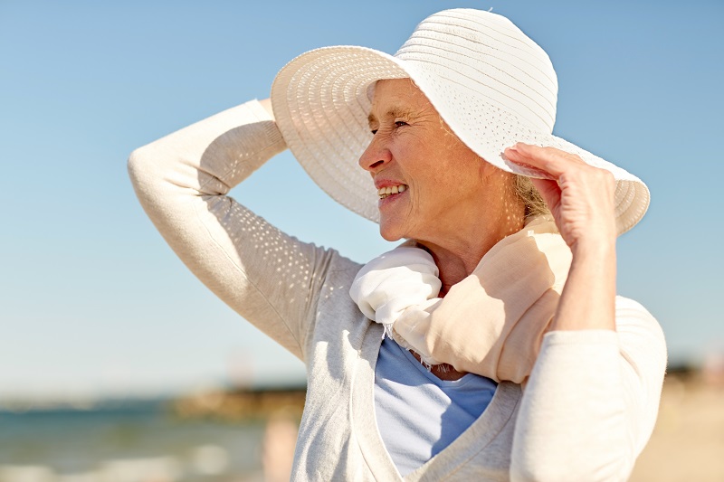 Mulher 60+ tomando sol na praia. Imagem ilustra a matéria sobre suplementação de vitamina D em pessoas 60+.