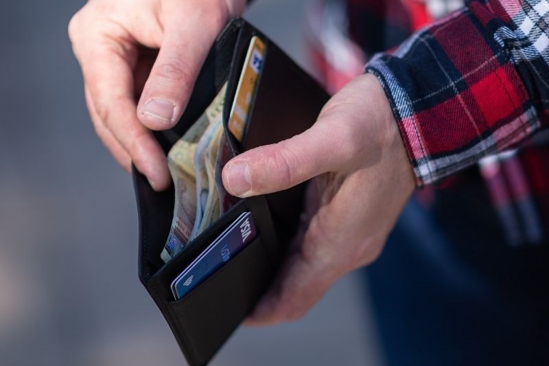 Uma mão de um homem abrindo uma carteira e tirando dinheiro. Imagem para ilustrar a matéria sobre salário mínimo de 2022.