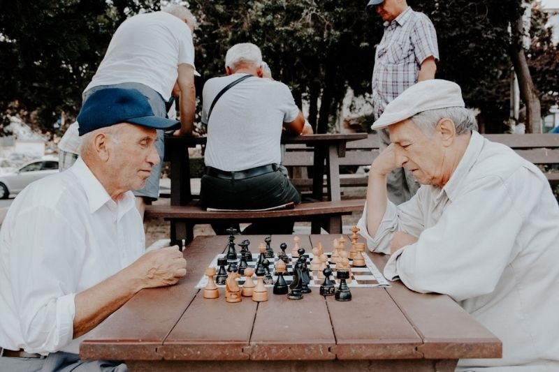 Um grupo de idosos jogando xadrez em uma praça. Imagem para ilustrar a matéria sobre a classificação do idoso.