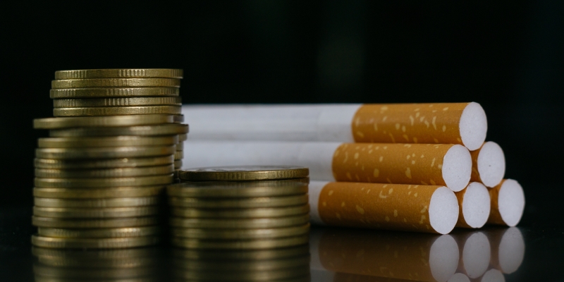 Sobre uma mesa, cigarros e moedas. Imagem para ilustrar a matéria sobre o Dia Nacional de Combate ao Fumo.