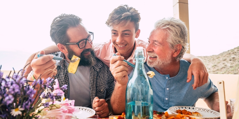 Pai, avô e filho comendo juntos se divertindo com tempo de qualidade. Celebração do conceito do dia dos pais com família de homens desfrutando de refeição na mesa. 