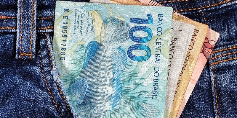 Um bolso com notas de dinheiro. Imagem para ilustrar a matéria sobre 13º em cota única.