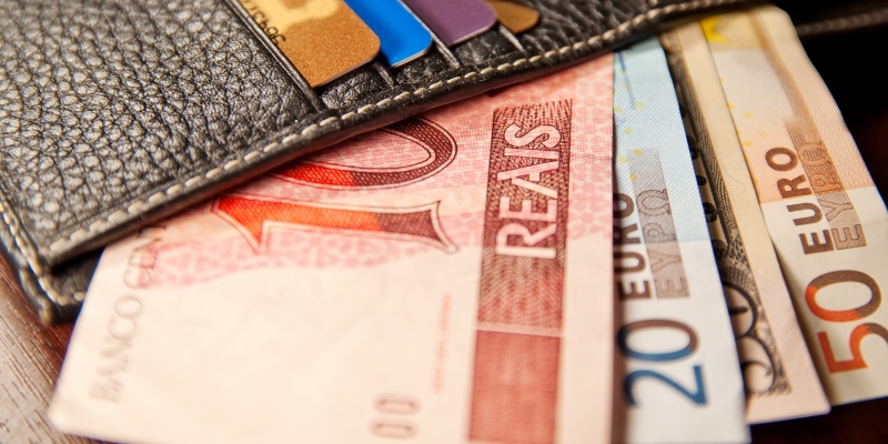 Uma carteira com notas em real e em euro. Imagem para ilustrar a matéria sobre aumentar o rendimento.