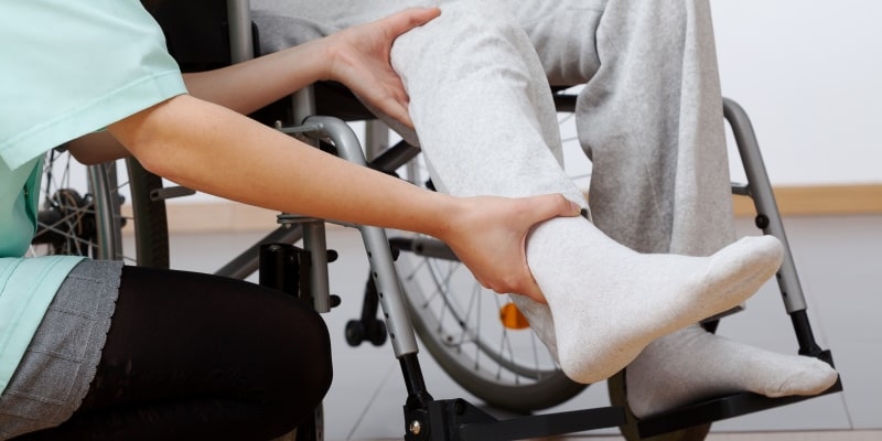 Jovem fisioterapeuta exercitando com pessoa deficiente idosa. Imagem para ilustrar a matéria sobre limitações físicas.