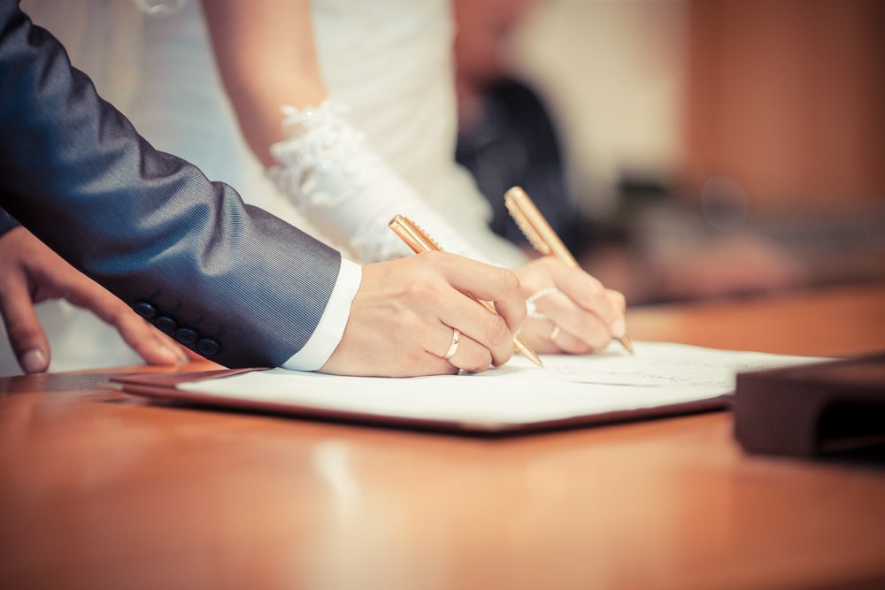 Um casal casando e assinando os papéis do casamento. Imagem para ilustrar a matéria sobre relacionamento.